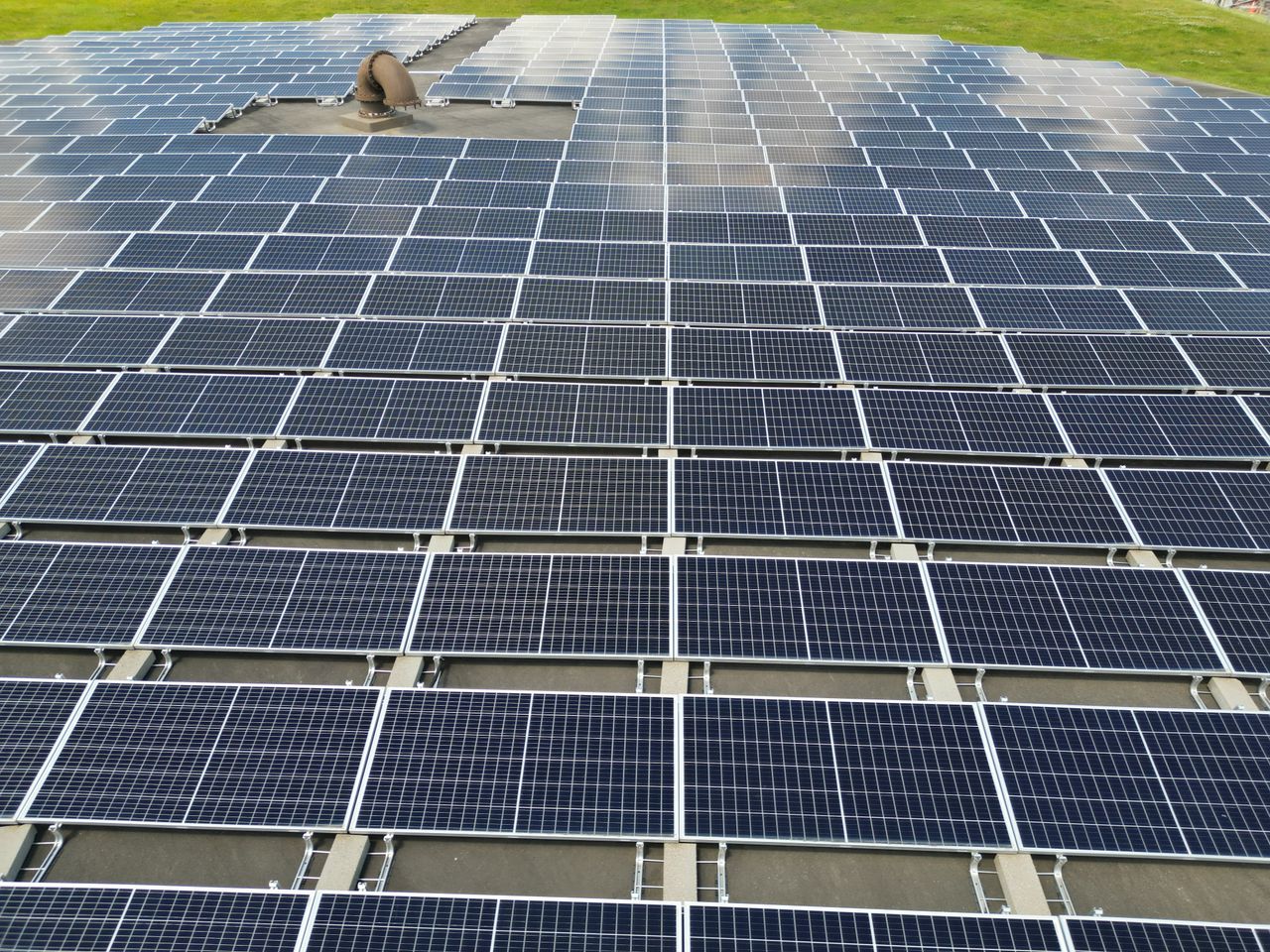 Home A large solar panel array on a sunny day in an open green field.